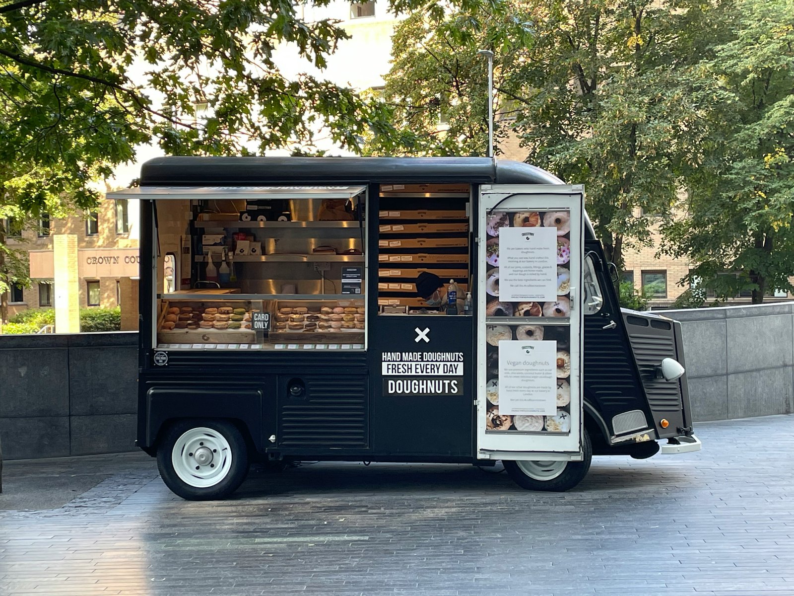 A black food truck with its side window open and a menu sitting out front.